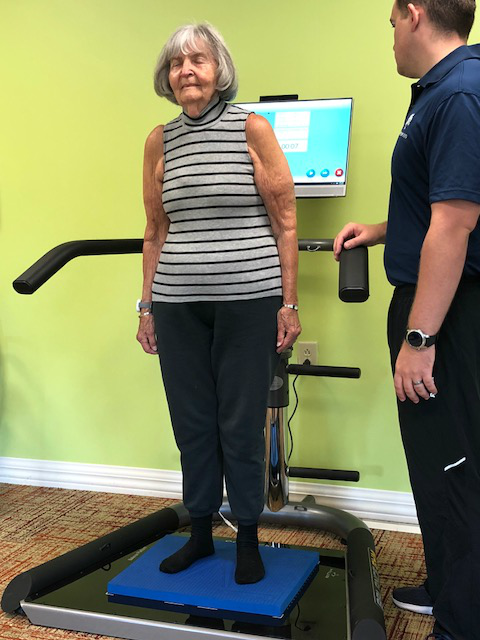 A senior woman uses a smartbalance machine to measure her balance skills and assist in fall prevention.