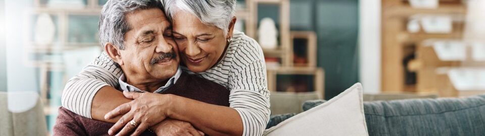 Cropped shot of a cheerful senior woman hugging her husband at home during the day.