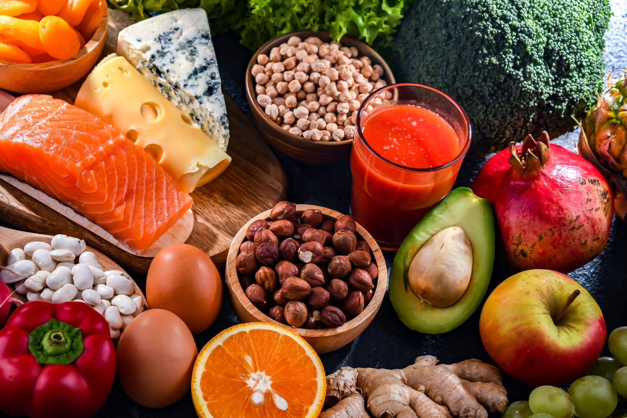 Healthy foods on a table like, a piece of salmon, bowl of red beans, eggs, fruit, & veggies...